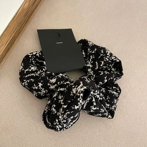 Detail of floral scrunchie in black and white with a paper tag on beige fabric background