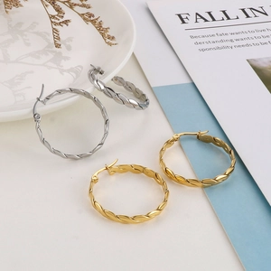 Macro detail of gold and silver twisted rope hoop earrings on a minimalist white background