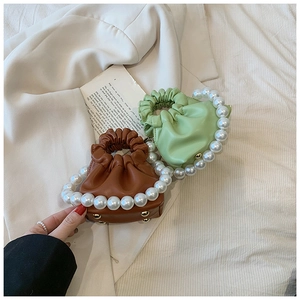 Detail of pleated mini bags in brown and light green with decorative pearl handles