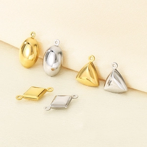 Macro view of geometric stainless steel pendants in gold and silver on soft fabric