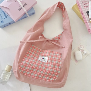 Close-up detail of a pink canvas hobo bag featuring a checkered pocket and bow tie