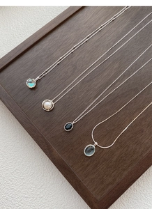Detail of four S925 silver necklaces with moonstone and pearl on a wooden tray