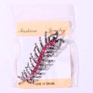 Détail de la broche mille-pattes argentée avec strass roses sur carte de présentation