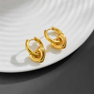 Close-up of golden stainless steel heart drop earrings on a white ceramic tray