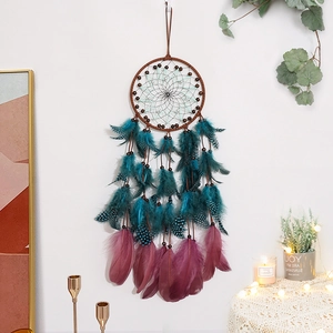 Handmade dreamcatcher with turquoise and purple feathers on white wall backdrop