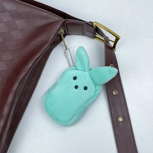Mint green plush bunny coin purse keychain attached to a brown checkered shoulder bag