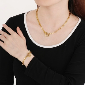 Dettaglio elegante del set collana e bracciale in oro con chiusura a cuore su una modella