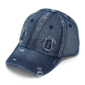 Detail of distressed navy blue denim baseball cap with vintage frayed holes and texture