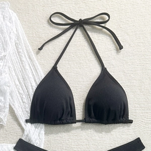 Close-up of black ribbed halter bikini top with bow tie detail on white textured blanket