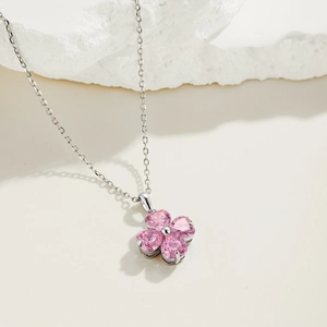 Detailed close-up of a silver clover pendant featuring four pink heart-shaped crystals