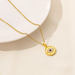Close-up of golden evil eye pendant with blue center stone and white zircon stones