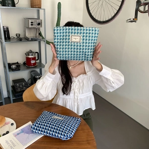 Gros plan de trousses à maquillage à carreaux avec étiquette Pleasant Time en bleu et blanc