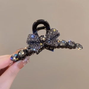 Detail of a grey bow hair claw clip with rhinestones and a large faceted gemstone