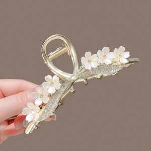 Detailed view of a gold floral hair claw clip featuring white petals and sparkling zircons
