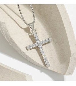 Macro shot of silver cross pendant with sparkling zircon stones on a classic box chain