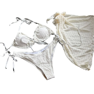 Three-piece white smocked bikini set with halter top and matching sarong skirt cover-up