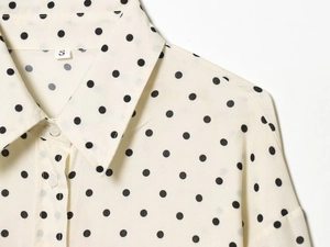 Close-up of the vintage polka dot lapel collar and woven fabric detail on the beige shirt
