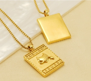 Detail view of gold-plated square pendant necklaces with devil heart relief and brushed finish