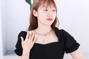 Detail of a silver double-layer heart pendant necklace on a model wearing black