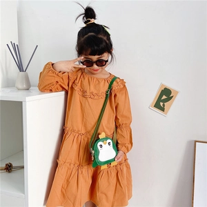 Cute green penguin cross-body bag for kids paired with a mustard yellow dress