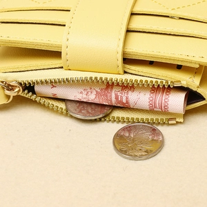 Dettaglio del portafoglio giallo con più scomparti per carte e tasca con zip scorrevole