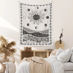 Detail of bohemian sun and moon tapestry with black geometric patterns on white background