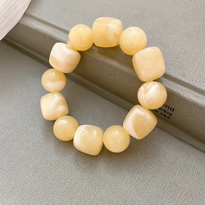 Gros plan d'un bracelet en perles acryliques crème avec perles rondes et carrées