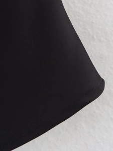 Détail du haut en satin noir montrant des coutures plates précises sur l'ourlet bas