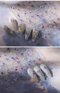 Detail showing 3D butterfly nail stickers in purple and blue with glitter on long false nails