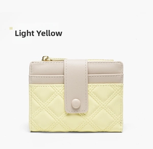 Detail of light yellow and beige PU leather wallet with quilted pattern and gold zipper