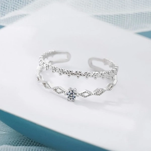 Macro detail of silver double-layer open ring featuring floral lace and diamond-cut zircon