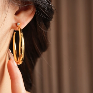Close-up of golden circular hoop earring with a small zircon stud on female model