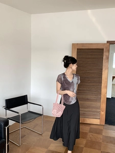 Tie-dye V-neck t-shirt paired with black maxi skirt and pink woven straw handbag