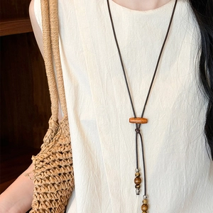 Ethnic style coconut wood bead necklace with heart pendant on a model with a straw bag
