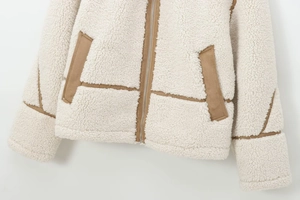 Détail de veste polaire avec fermeture éclair et bordures en daim sur tissu crème