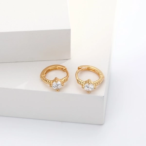 Close-up of gold S925 sterling silver hoops with zircon on white stone blocks