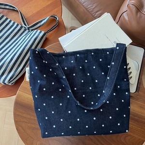 Close-up of a dark blue polka dot denim tote bag on a rustic wooden table for a cozy vibe