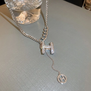 Detail of silver H-shaped pendant necklace with crystal inlay and layered chain
