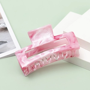 Pink marble texture resin square hair claw clip on white geometric stand with soft green background