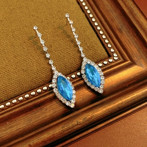 Macro detail of blue marquise-cut crystal earrings with tassels on vintage velvet