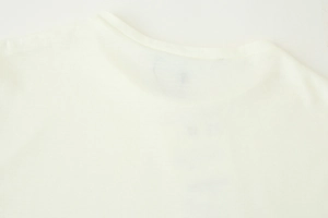 Détail des coutures de l'encolure ronde et texture du tissu tricoté sur robe crème
