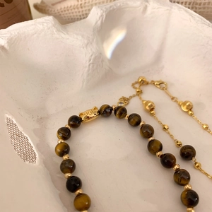 Tiger eye beaded bracelet with gold cat charm and fine chain necklace on white background