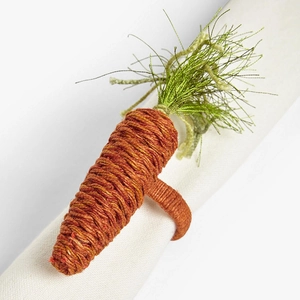 Detailed view of handmade woven carrot napkin ring with green leaves on white napkin