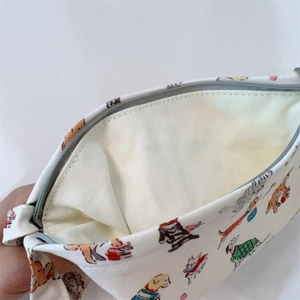 Gros plan de la pochette en coton ouverte avec motifs chiots mignons et fermeture éclair