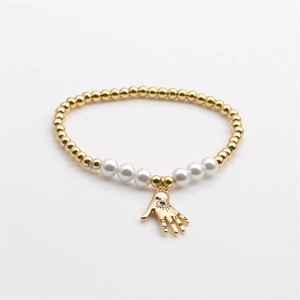 Gold plated bead and pearl bracelet featuring Hamsa Hand charm on white background
