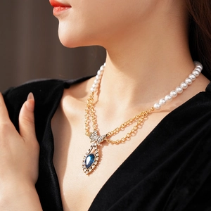 Detail of vintage necklace with pearls, blue teardrop gem and bow worn by model