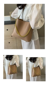 Detail of camel leather tote bag with decorative gold chain and long shoulder strap