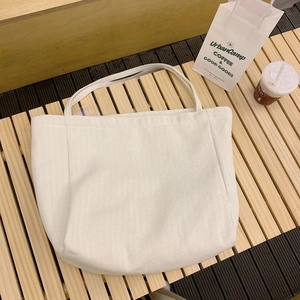 Minimalist cream canvas tote bag with herringbone texture on a wooden bench