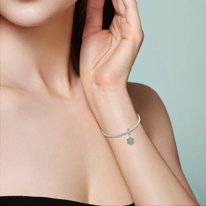 Bracelet argenté avec pendentif flocon et chaîne serpent sur le poignet d'une femme