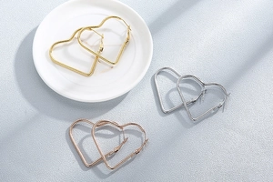 Detailed view of heart-shaped hoop earrings with spiral twist texture in three metal colors